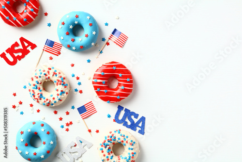 Flat lay USA donuts  American flags  confetti isolated on white background. 4th of July party invitation card design.