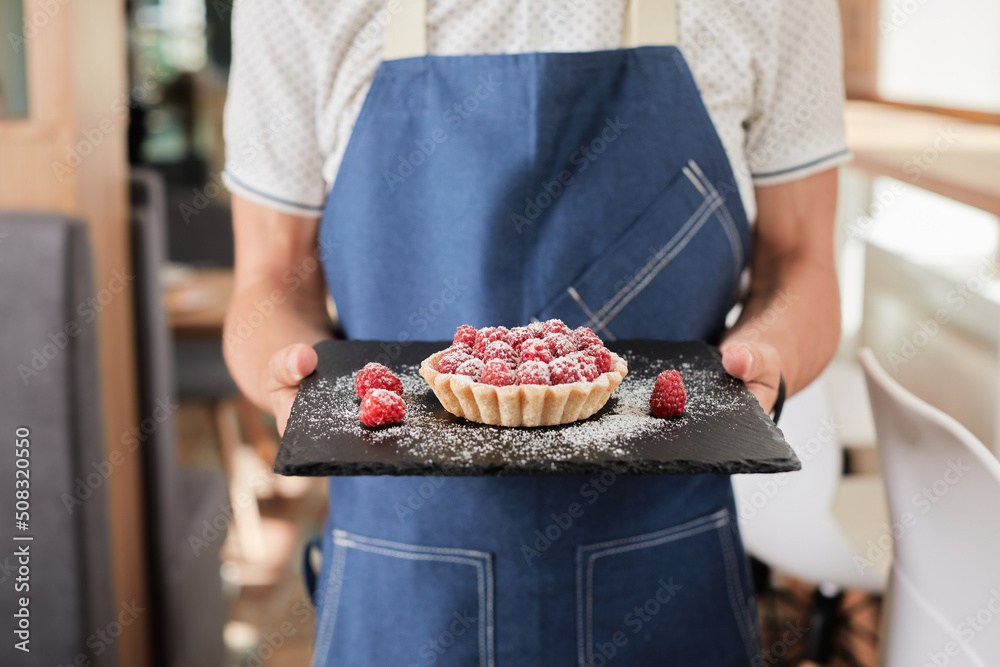 guy holding a dessert with raspberries close-up