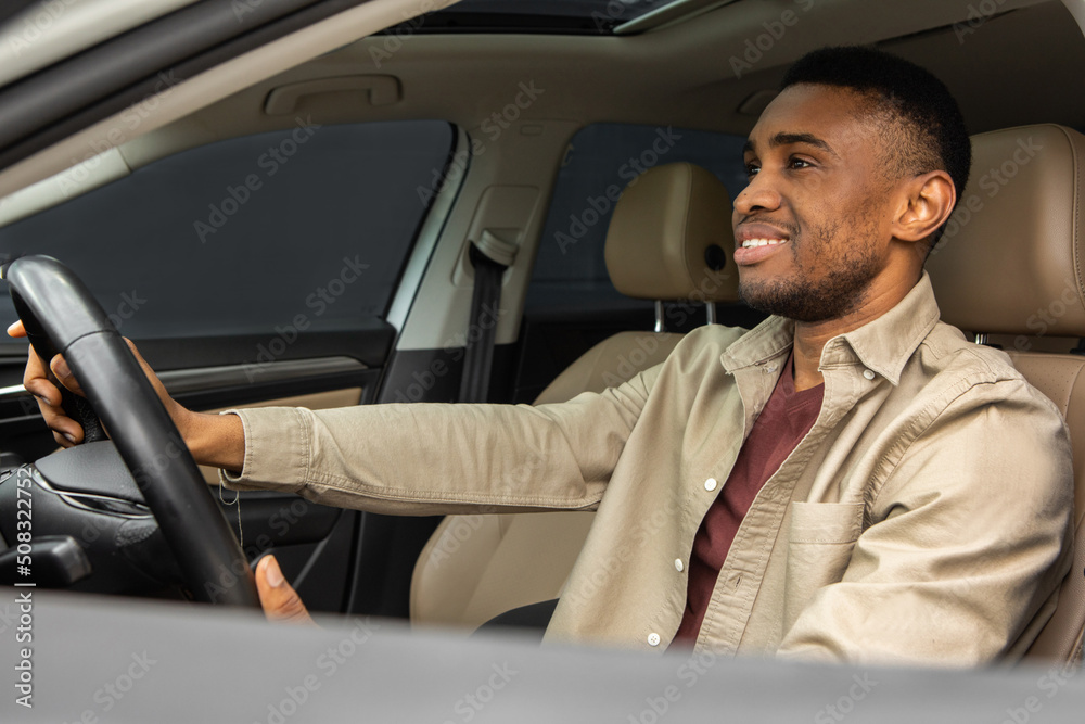 Side portrait of happy young african male driver driving a car