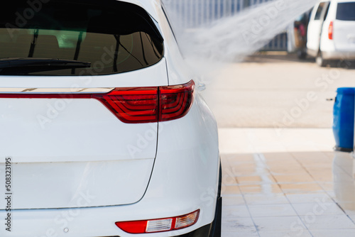 self-service car wash. a person washes the car from a hose. 