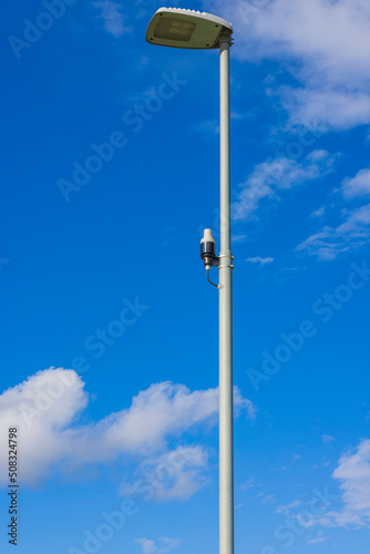 Close up view of light sensor on street lighting pole on blue sky with rare white clouds background. Sweden. 