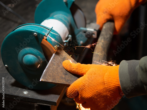 Tableau sur toile man sharpening an ax blade on a grinder