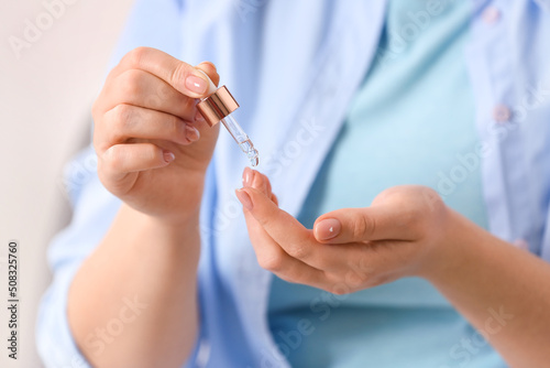 Woman applying serum onto hand  closeup