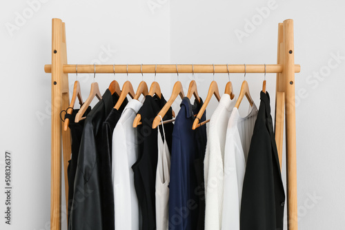 Wooden rack with female clothes near light wall photo