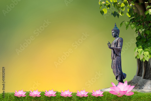 Leinwand Poster Buddha statue standing under bodhi tree on bokeh nature background