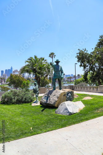 a green bronze statue of General Douglas MacArthur in the park surrounded by lush green palm trees and green grass with blue sky at MacArthur Park in Los Angeles California USA photo