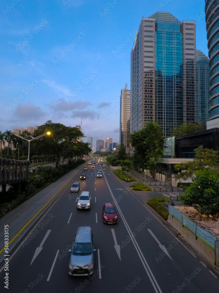 urban road traffic with view of tall buildings and blue clouds