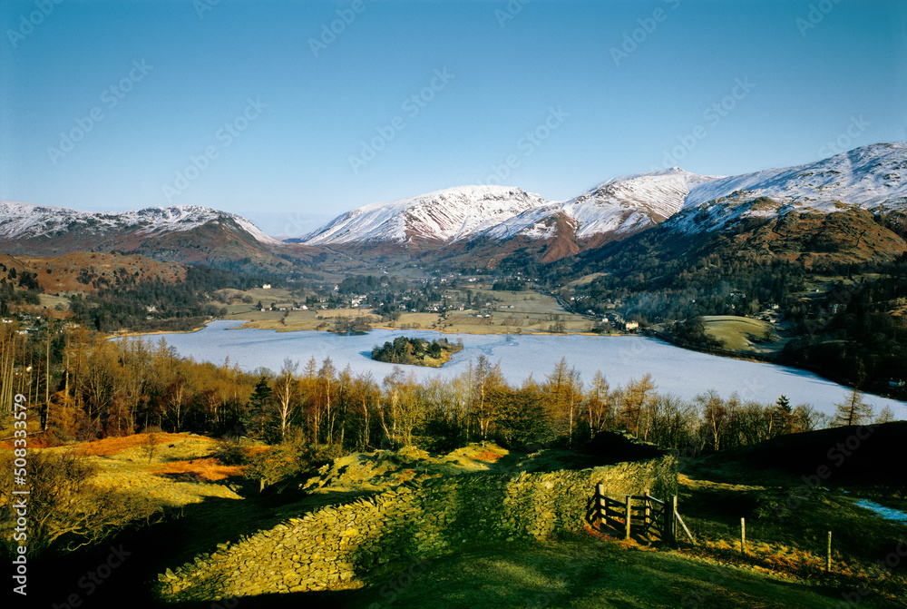North over Grasmere valley village in Lake District National Park, Cumbria, England. Frozen lake and snow on mountains. Winter.