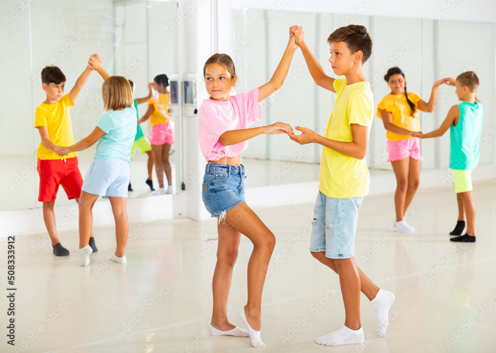 Young boys and girls dancing salsa in studio during group training.