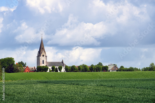 Landscape with Vadensjo church on a very windy summer day on the Swedish countryside in Skane, Sweden. Shallow depth of field. Selective focus. photo