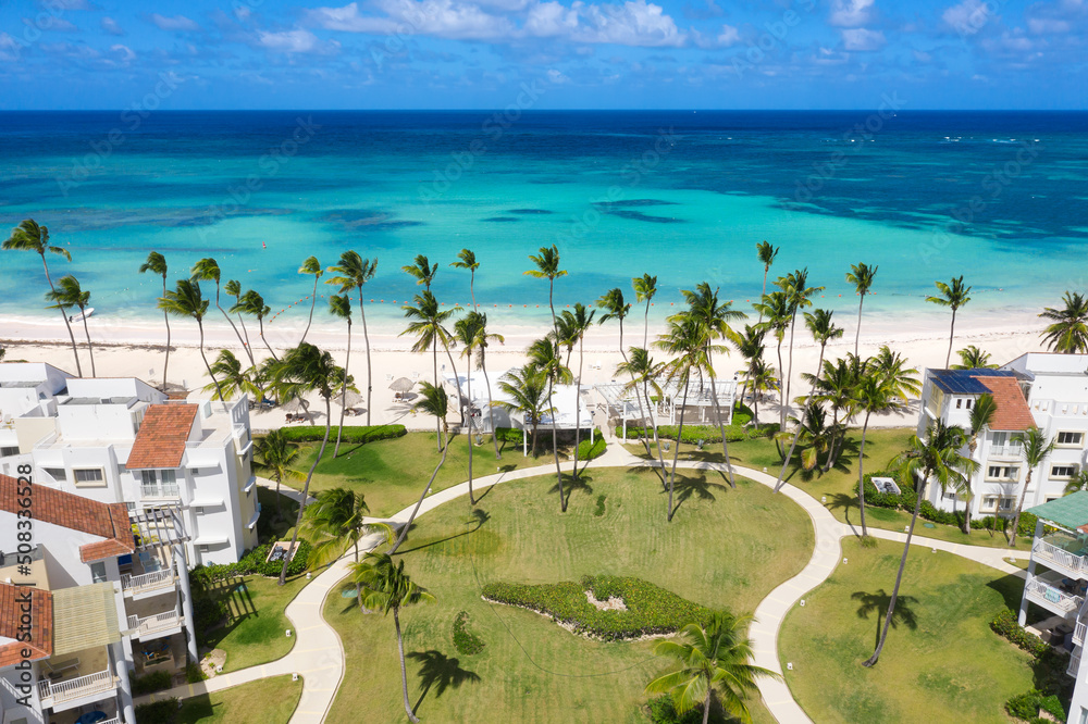 Caribbean beach of Atlantic ocean with luxury resort, coconut palm trees and azure water. Travel destination for vacation. Aerial view - obrazy, fototapety, plakaty 