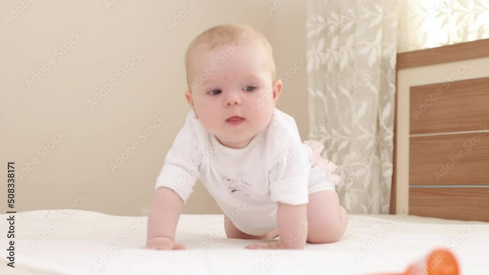 Beautiful smiling Baby girl lies on the bed, looks at camera and smiles with a nice soft focus domestic background. Beautiful smiling Baby girl lies on the bed, looks at camera and smiles with a nice soft focus domestic background.