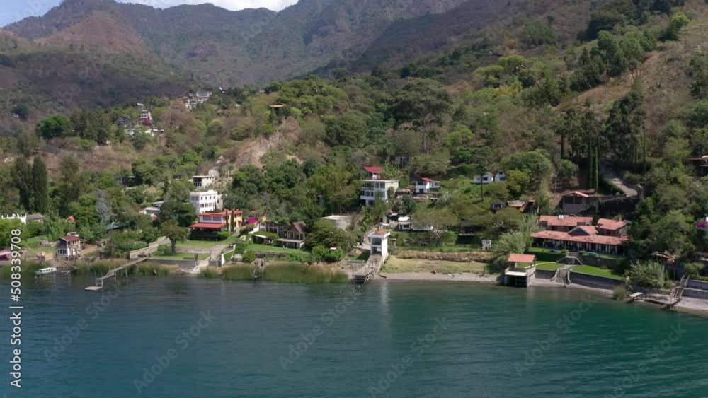 Aerial drone forwarding shot over hotels, resorts and residential houses on the banks of lake Atitlan, Guatemala, Central America surrounded by volcanic mountain range. Aerial drone forwarding shot over hotels, resorts and residential houses on the banks of lake Atitlan, Guatemala, Central America surrounded by volcanic mountain range.