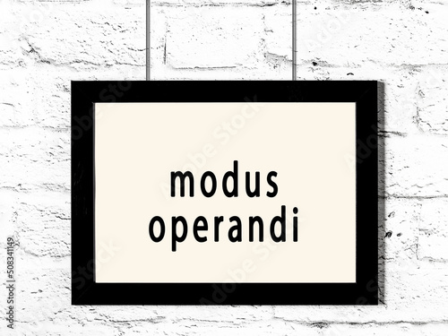 Black frame hanging on white brick wall with inscription modus operandi photo