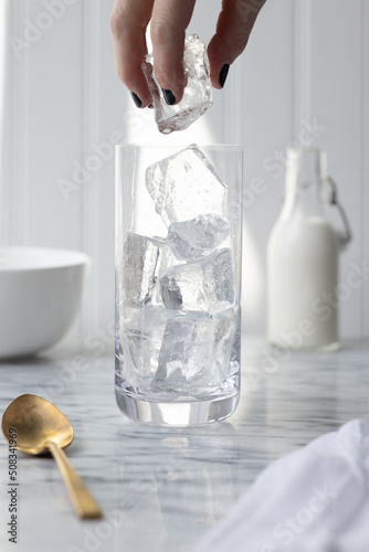 Glass being filled with clear ice by woman