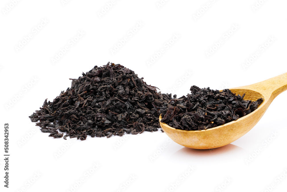 Black loose long leaf tea in wooden spoon next to tea heap isolated on white background Black loose long leaf tea in wooden spoon next to tea heap isolated on white background