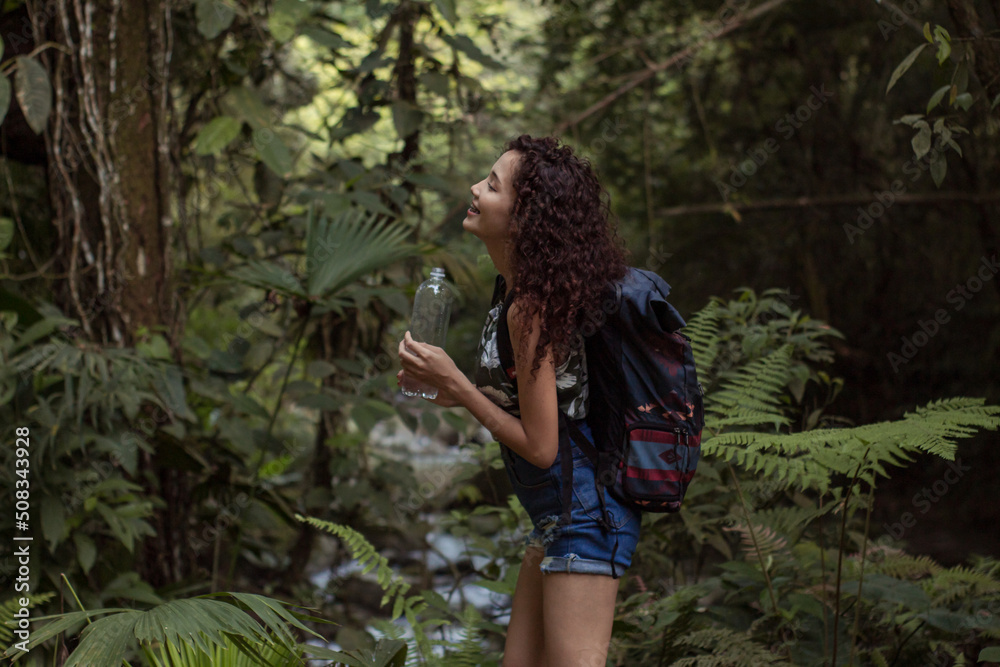 girl on a walk through the forest while enjoying nature and drinking water girl on a walk through the forest while enjoying nature and drinking water
