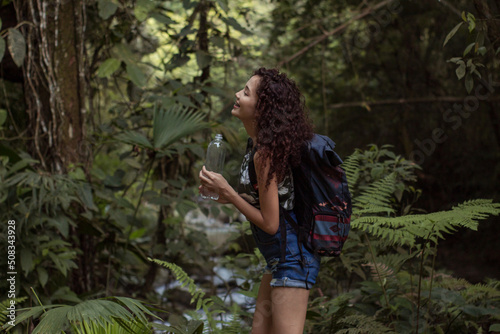 girl on a walk through the forest while enjoying nature and drinking water