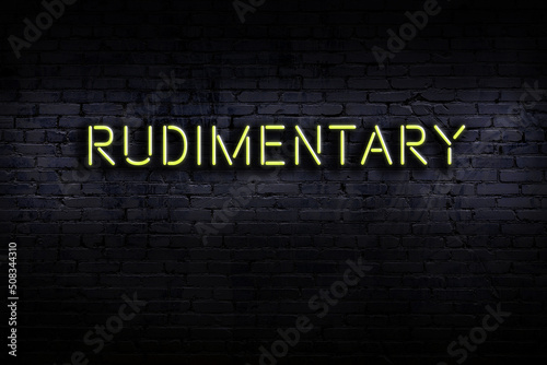 Slika na platnu Night view of neon sign on brick wall with inscription rudimentary