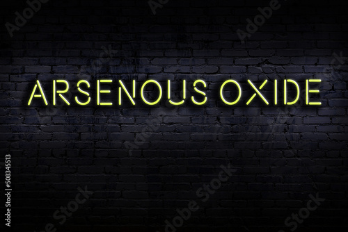 Neon sign. Word arsenous oxide against brick wall. Night view photo