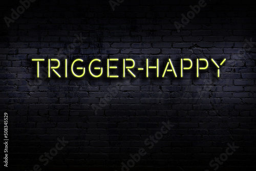 Neon sign. Word trigger-happy against brick wall. Night view photo