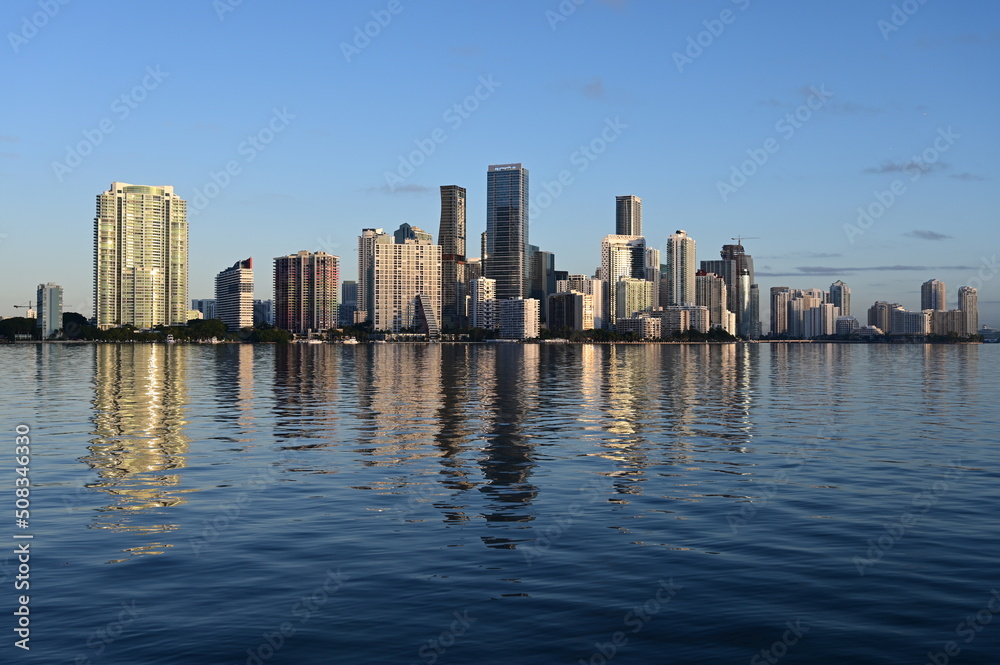 Skyline of City of Miami, Florida reflected in calm water of Biscayne Bay on clear sunny morning.
