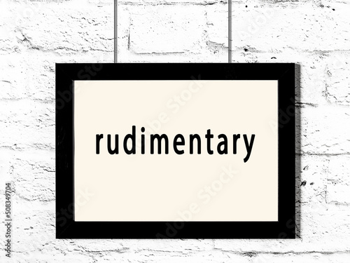 Fotografie Black frame hanging on white brick wall with inscription rudimentary