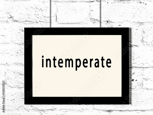 Black frame hanging on white brick wall with inscription intemperate photo