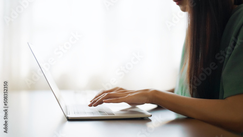 Hand of woman typing on computer laptop keyboard at house