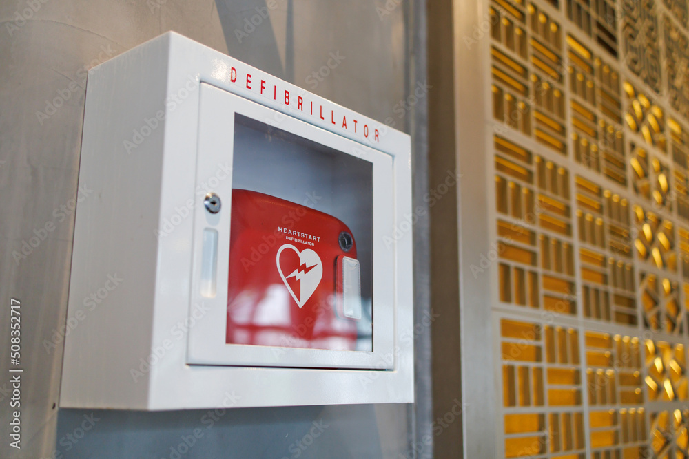 An automated external defibrillator box in a commercial building. It is a lightweight, portable device that delivers an electric shock through the chest to the heart. - obrazy, fototapety, plakaty 