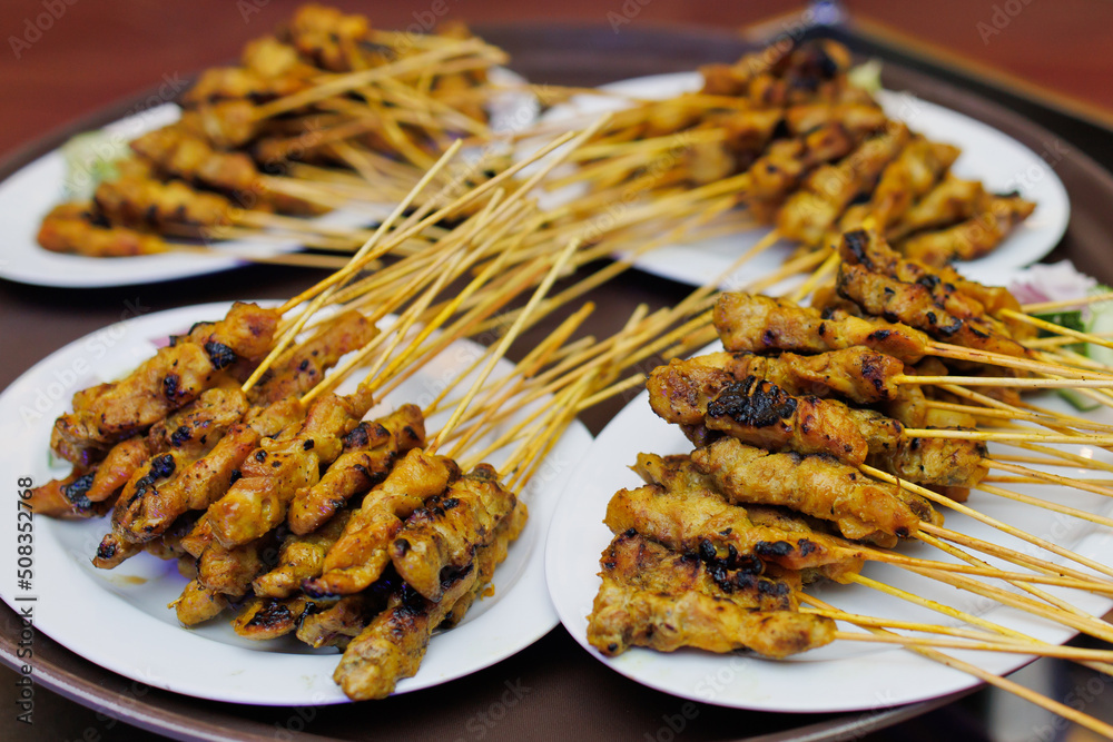Chicken satay with delicious peanut sauce, onion and cucumber. One of the famous local street food in Malaysia. Soft focus image.
