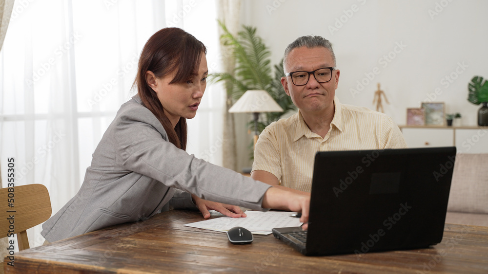 asian female insurance agent showing information on computer and answering the senior customer’s questions while they are discussing long-term care plans at home asian female insurance agent showing information on computer and answering the senior customer’s questions while they are discussing long-term care plans at home