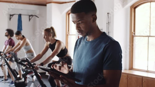 Confident, knowledgable young adult black male using tablet at an indoor fitness gym photo