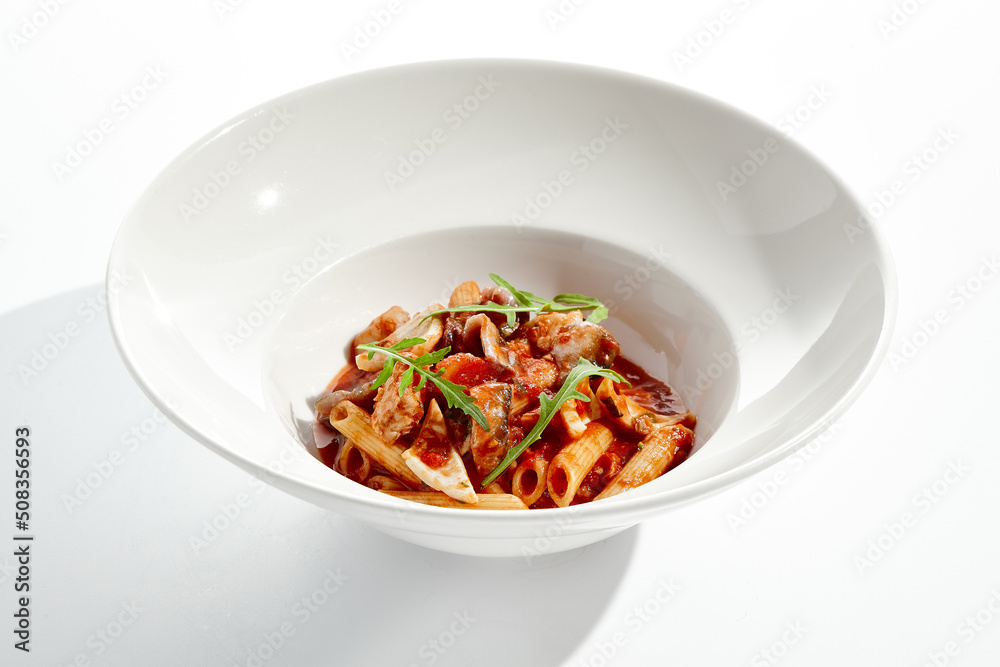 Traditional Italian dish - penne with salmon and squid with tomato sauce and olives. Penne marinara with seafood on white table. Italian seafood pasta in arrabiata sauce - healthy mediterrian lunch. Traditional Italian dish - penne with salmon and squid with tomato sauce and olives. Penne marinara with seafood on white table. Italian seafood pasta in arrabiata sauce - healthy mediterrian lunch.