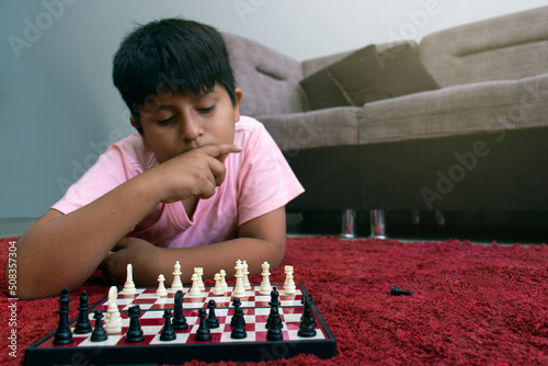 little boy playing chess at home photo