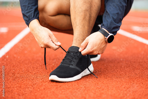 Hands man runners tie shoelaces prepared to run on track. Young asian man wearing sportswear running sport stadium.Training athlete work out at outdoor concept.