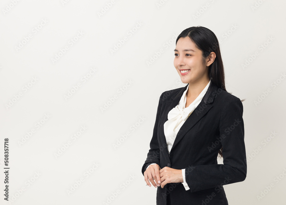 Young asian business woman smiling standing looking at blank space on isolated white background. Female around 25 in suit portrait shot in studio. Young asian business woman smiling standing looking at blank space on isolated white background. Female around 25 in suit portrait shot in studio.