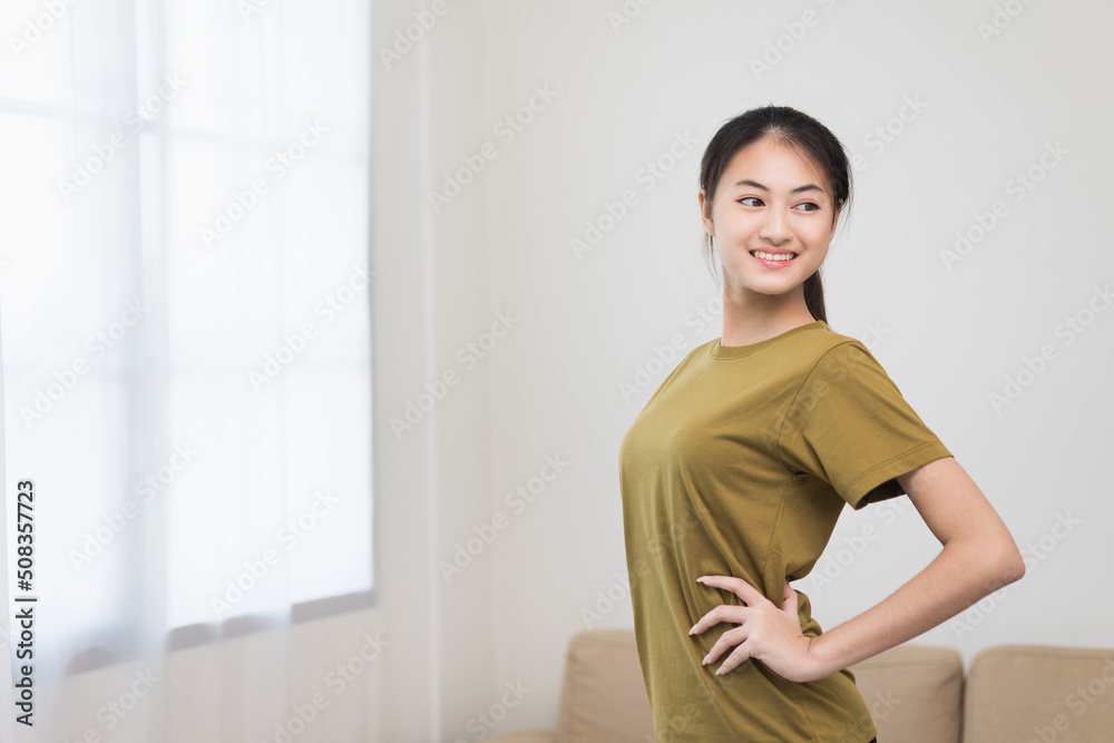 Young beautiful asian woman standing pose smiling to camera. Cheerfully sporty female workout and exercise wearing sport wear at home. Charming woman fitness training and stretching in living room Young beautiful asian woman standing pose smiling to camera. Cheerfully sporty female workout and exercise wearing sport wear at home. Charming woman fitness training and stretching in living room
