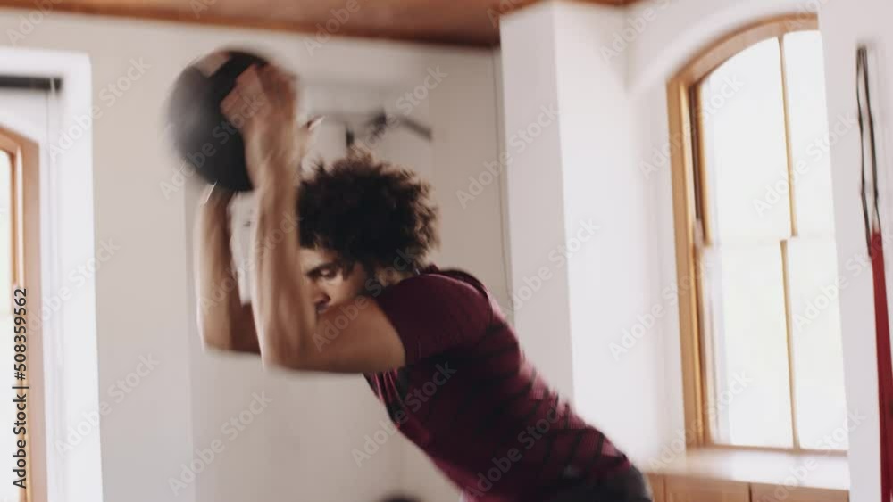 Young adult middle eastern male slamming ball to ground at an indoor fitness gym