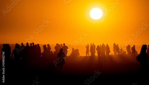 Silhouette of people looking toward the sun on a misty beach