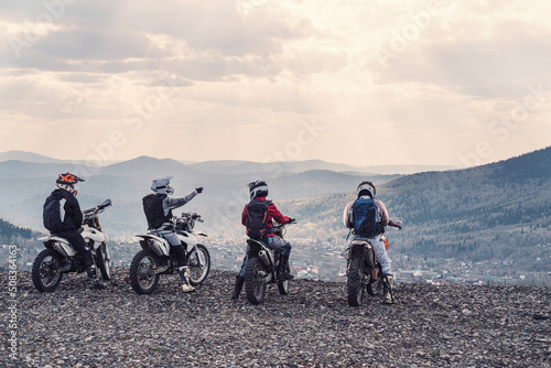 Fototapeta group motorcyclists traveling in mountains on dirt motorcycles, standing and enj