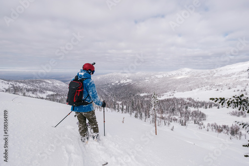 Skier walking alone standing on mountainside in deep snow
