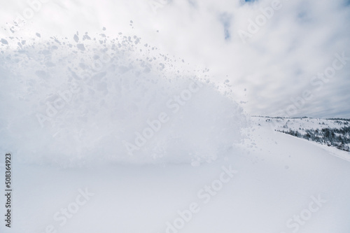Splashes of snow from passing skier, snow explosion on hillside