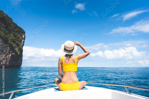 Rear view of young adult traveling tourist woman sit on the sailing boat on summer vacation trip in southeast asia