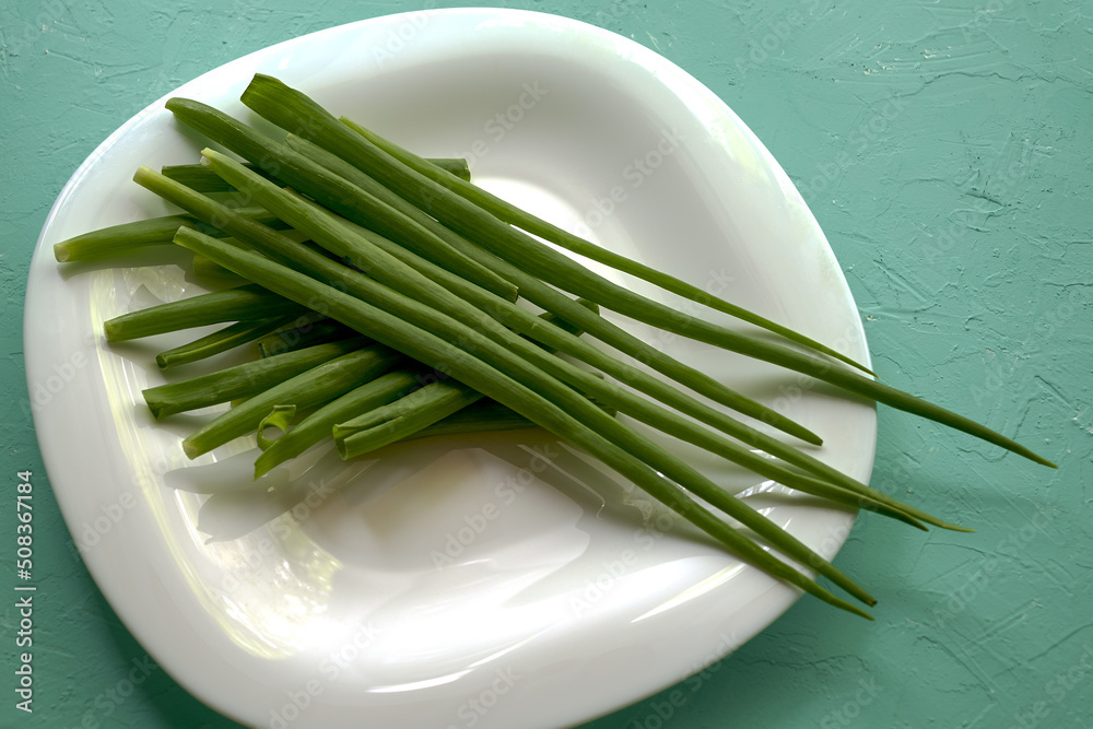 green onion leaves on a white plate on the table green onion leaves on a white plate on the table