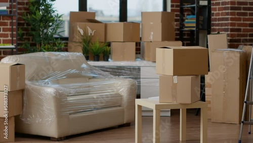 No people in empty living room apartment with carton boxes on stack, moving cardboard storage packaging in new household. Nobody in relocation property with interior furniture cargo. photo
