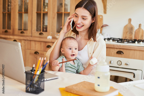 Working mom making notes during a phone call with her clients.