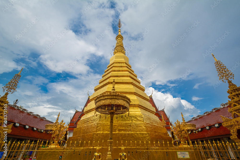 Fototapeta premium The gold pagoda in Wat Phrathat Cho Hae, Phrae province, Thailand. This gold pagoda is famous and was built on a mountain.
