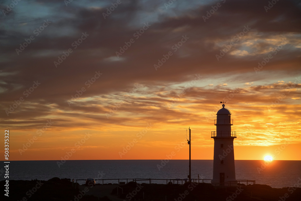 Lighthouse silhouette against the backdrop of the ocean and sunset, evening clouds sky and clouds, landscape
