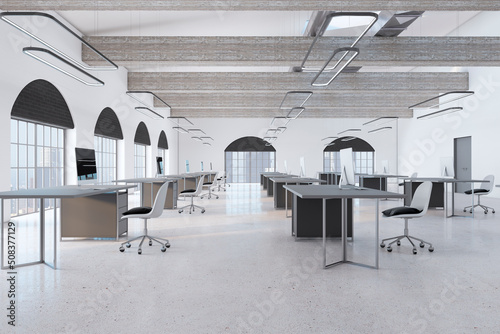 Luxury coworking office interior with empty computer screens on desks, concrete flooring and window with city view. Workplace concept. 3D Rendering.